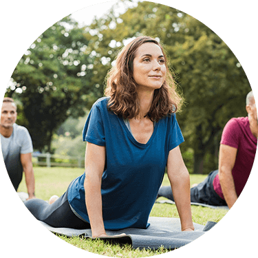 Older woman doing a yoga pose at a yoga class in a field.