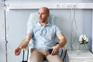 Adult man sitting in chair with IV drip during treatment session