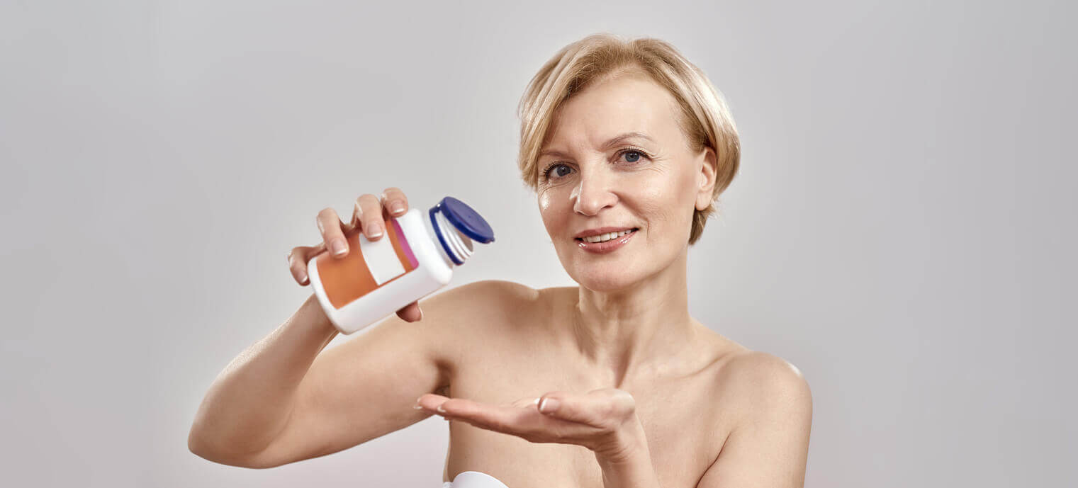 A middle-aged Caucasian woman smiles at the camera while pouring pills resembling Rapamycin from a bottle to illustrate anti-aging and longevity.