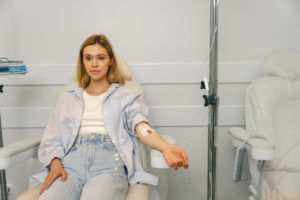 A woman is sitting in an armchair while receiving an IV hydration therapy as part of her treatment in the hospital.