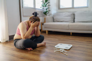 An obese woman is frustrated and unhappy with her weight loss journey due to repeated dieting failures.