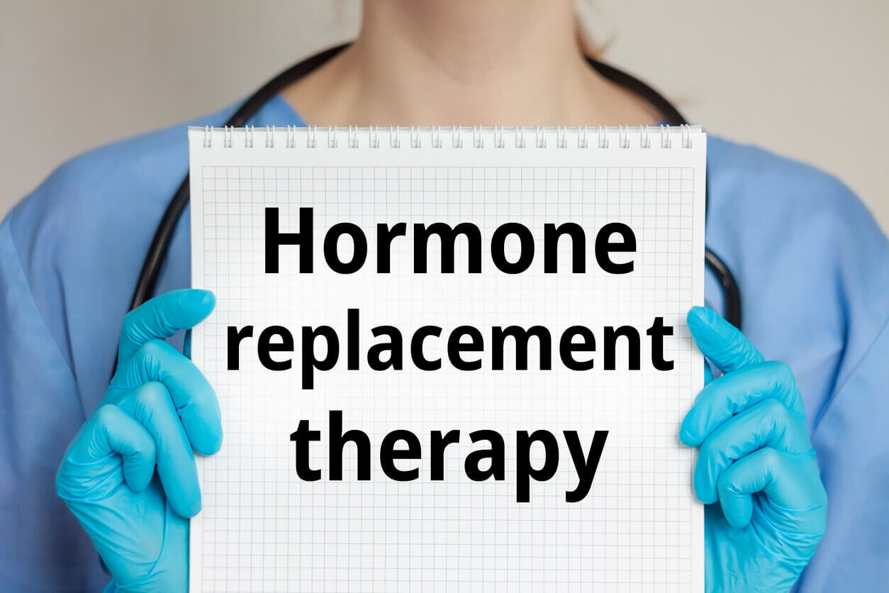 A female healthcare provider holds a journal inscribed with Hormone Replacement Therapy.