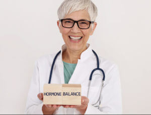 A female gynecologist holding a wooden board with the text Hormone Balance written on it.