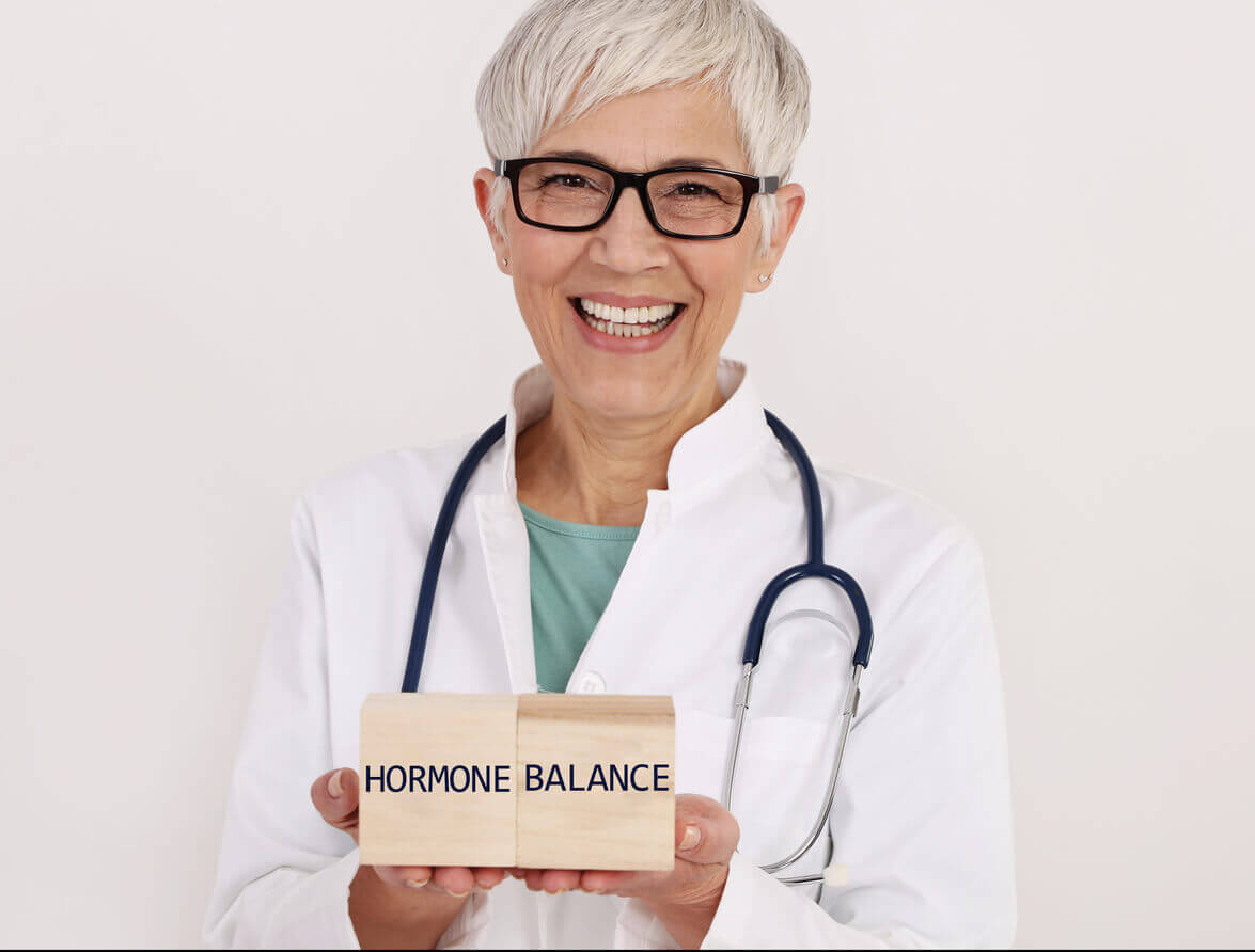 A female gynecologist holding a wooden board with the text Hormone Balance written on it.