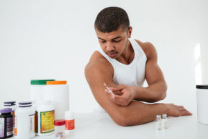 A man standing against a white background holding Testosterone injections for low testosterone therapy.