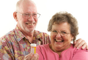 A smiling senior couple is holding a Rapamycin medication for longevity enhancement.