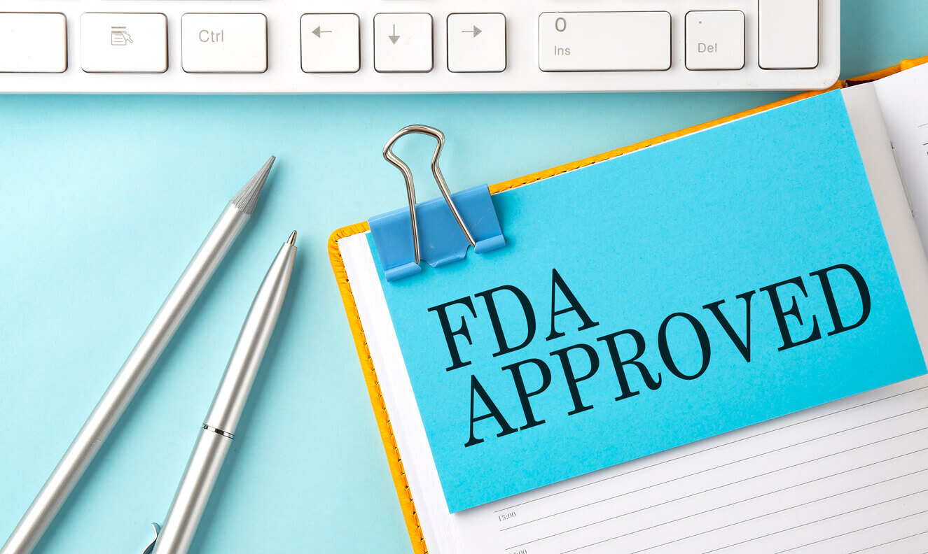 FDA APPROVED text on sticker on the blue background with pen and keyboard.