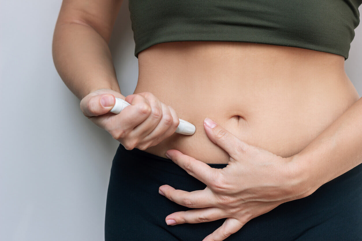 Young woman putting a hormonal injection in her stomach with pen syringe