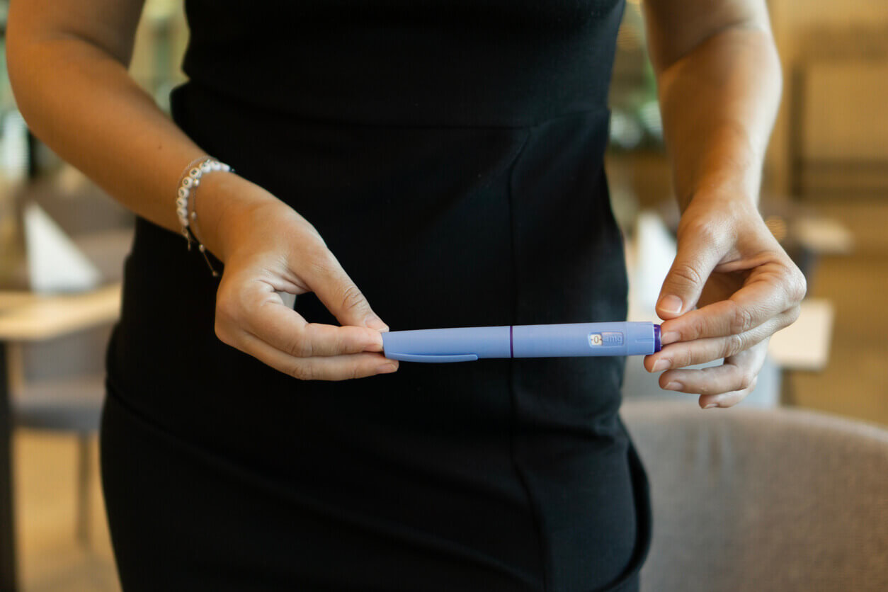 A woman in a black dress holding an ozempic pen