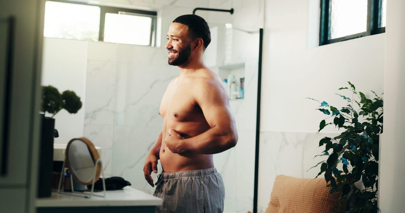 Happy man, belly and weightloss in bathroom for personal care or self confidence at home.