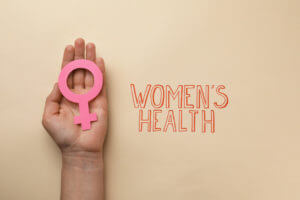 Girl holding female gender sign near text Women's Health on beige background