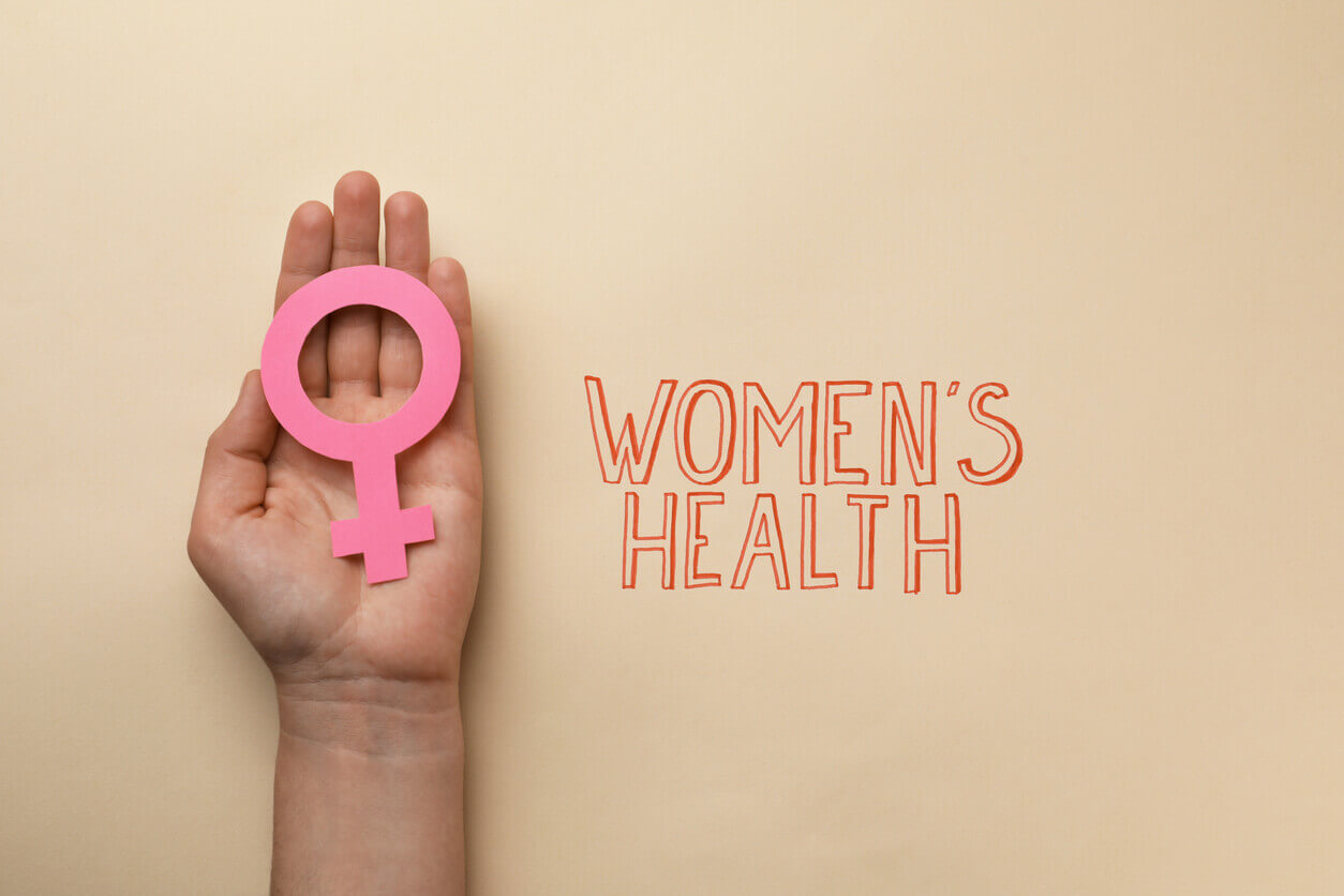 Girl holding female gender sign near text Women's Health on beige background